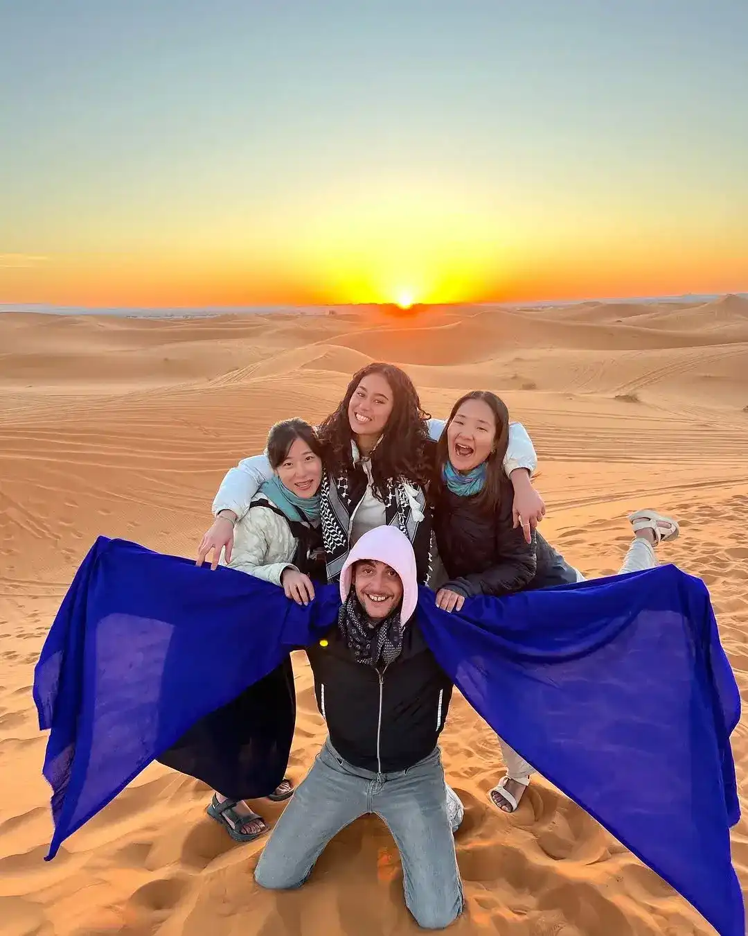 A group of friends celebrating sunrise on top of a dune